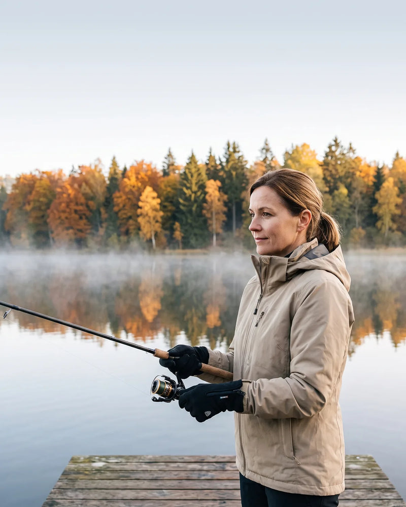 Frau mit beheizten Handschuhen beim Angeln am See