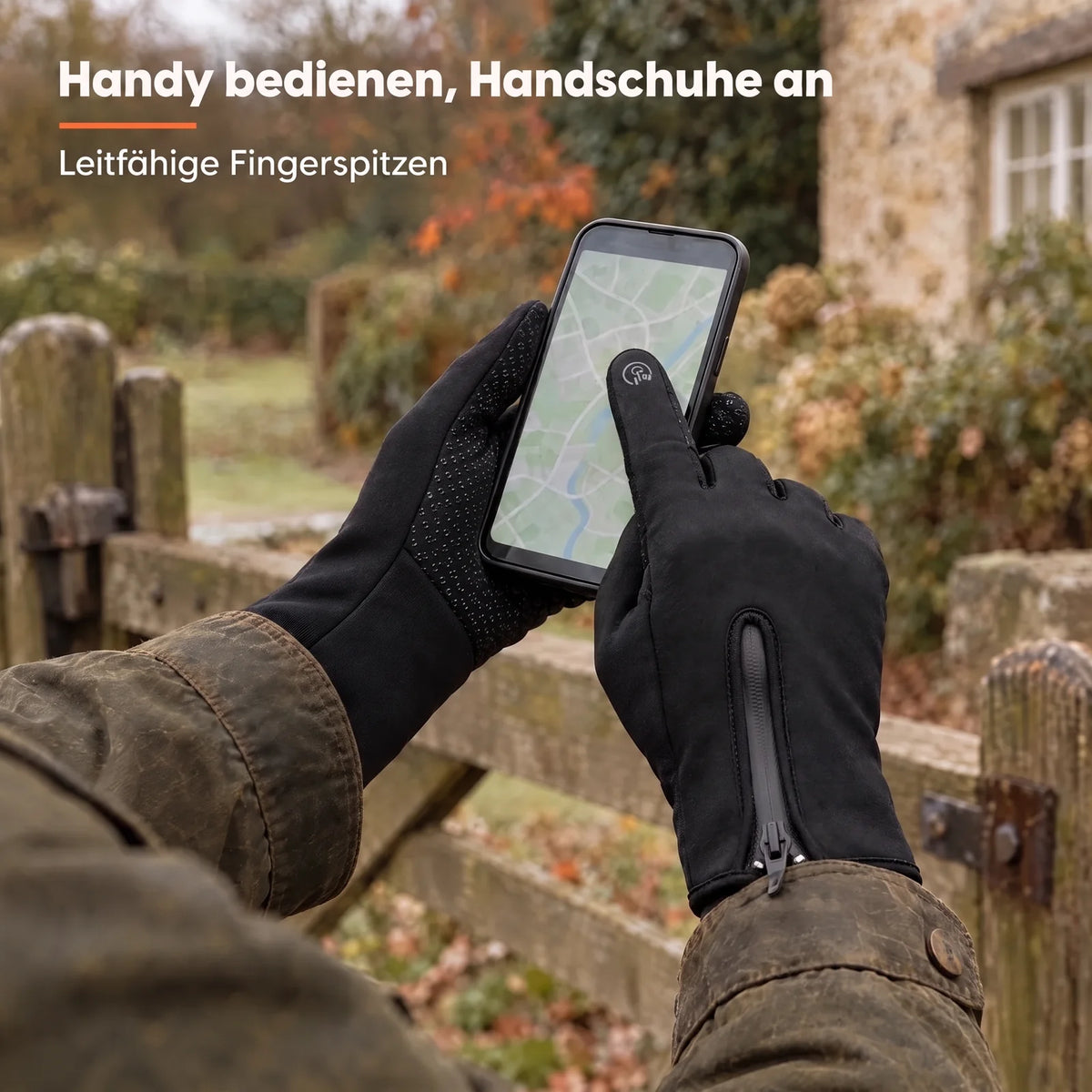 Hände in den Griff-Handschuhen bedienen am Gartentor ein Smartphone