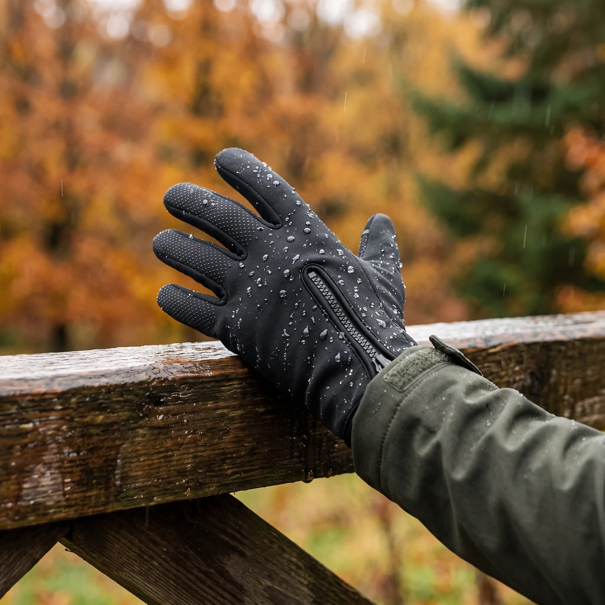 Wassertropfen perlen auf dem beheizten Handschuh Griff an einem nassen Holzgatter im Herbst