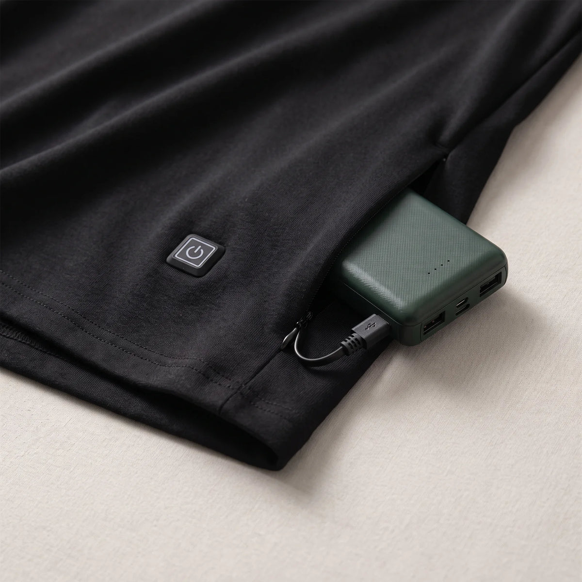 Heizknopf am Saum und Reißverschlusstasche mit angeschlossener BergHeat Powerbank